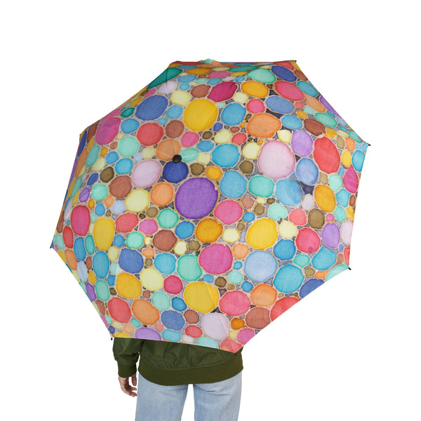 Colorful umbrella with a pattern of multicolored circles held by a person on a white background