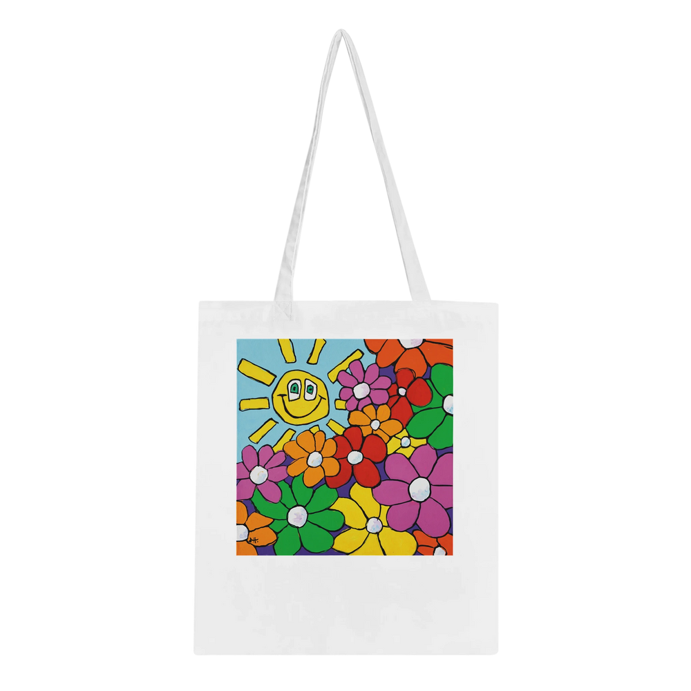 A high-quality white canvas tote bag featuring "Bouquet & Sun," a vibrant original artwork by MFPA mouth painter Lars Hollerer, depicting a cheerful smiling sun and a colorful garden of flowers.