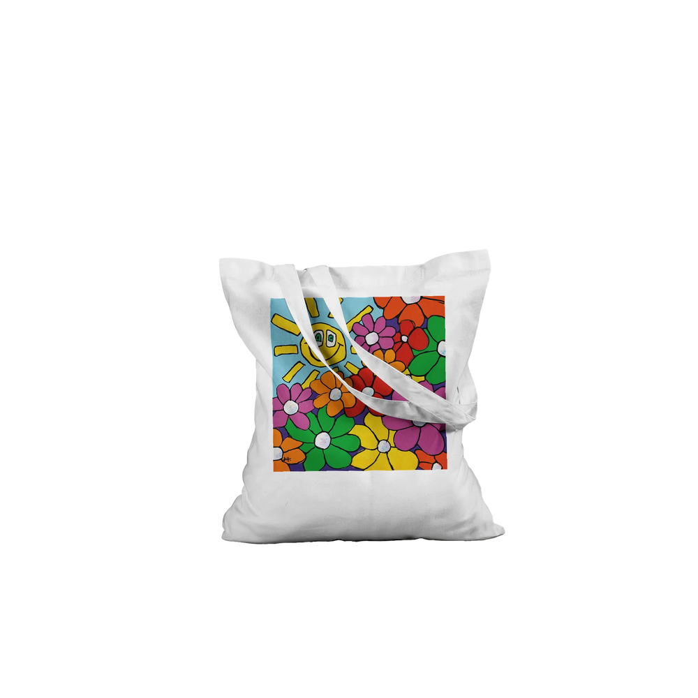 A high-quality white canvas tote bag featuring "Bouquet & Sun," a vibrant original artwork by MFPA mouth painter Lars Hollerer, depicting a cheerful smiling sun and a colorful garden of flowers.