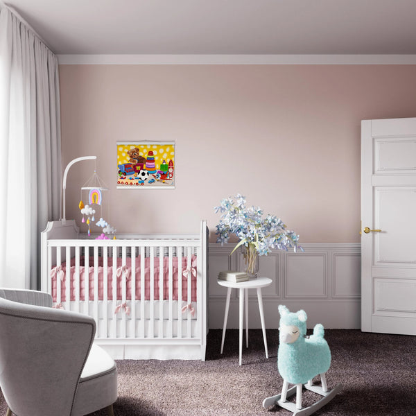 Shows a bright, whimsical children's painting titled "The Toybox" by MFPA artist Lars Hollerer, hanging in a soft pink nursery above a white crib. The artwork features a teddy bear, a soccer ball, and colorful toys against a cheerful yellow background.